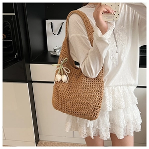 Detailed close-up of straw woven shoulder bag with tulip charm and pearl ribbon decor