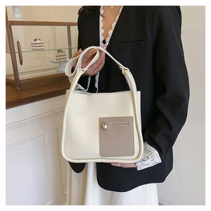 Close-up of cream textured leather shoulder bag with brown zipper pocket and metal lock