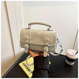 Detail view of light green PU leather handbag with dual bow accents and silver metal buckle