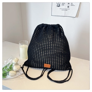 Detail of black crochet drawstring bucket bag with hollow mesh and orange leather tag