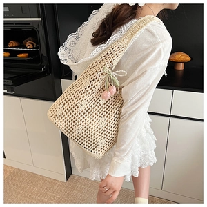 Detail of beige crochet tote bag featuring pearl bow and pink tulip floral charms