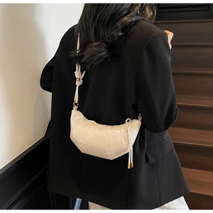Close-up of cream crescent bag with segment stitching and glossy leather finish