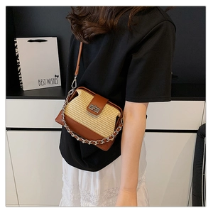 Detail of straw and leather crossbody bag with metal chain strap and turn-lock closure