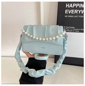 Detail of light blue pleated cloud bag with elegant pearl chain and soft PU leather texture