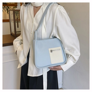 Close-up of light blue lychee pattern shoulder bag with beige pocket on female model