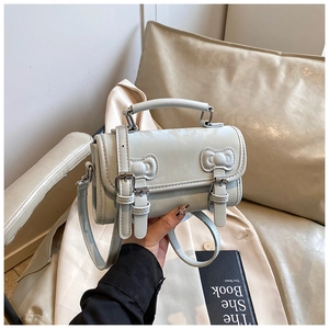 Close-up of mint blue PU leather crossbody bag with bow details and top handle