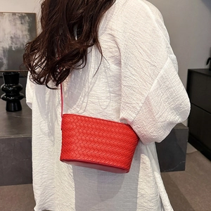 Detail of red woven mini bucket bag featuring intricate crisscross leather craftsmanship