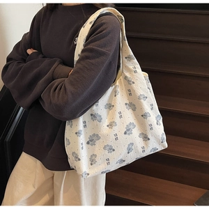 Detail of white canvas tote bag featuring grey goldfish patterns and koi characters