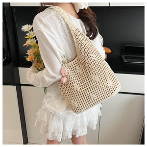 Detail of hollow woven shoulder bag in beige with pink tulip charm and mesh texture