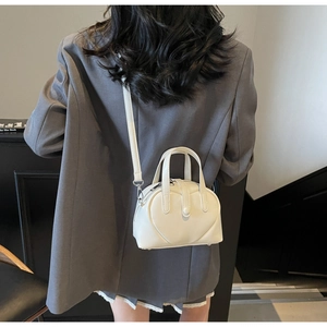 Crossbody view of white heart-shaped mini handbag with silver zippers and adjustable strap