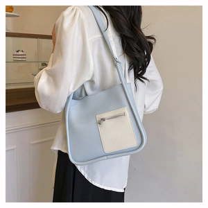 Detail of light blue lychee pattern shoulder bag with beige front zipper pocket