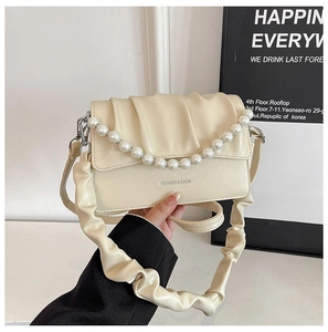Detail of cream pleated cloud bag with pearl handle and silver logo on shoulder strap