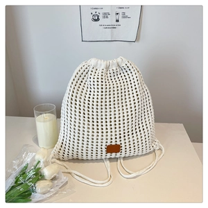 Detail of hollow knitted mesh texture and leather logo on beige drawstring bucket bag