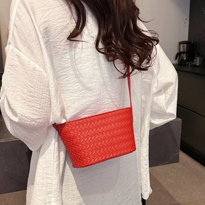 Detail of red woven leather crossbody bag texture worn with a white blouse