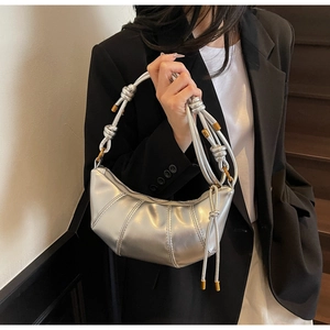 Detail of silver half-moon bag with metallic pleats and braided knot strap detail