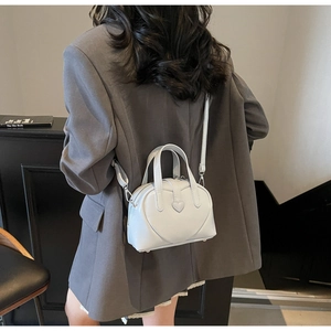Rear view of a model wearing a light grey heart-shaped Boston bag with quilted texture