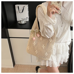 Detail of beige crochet tote bag featuring pink tulip charm and pearl bow accessory
