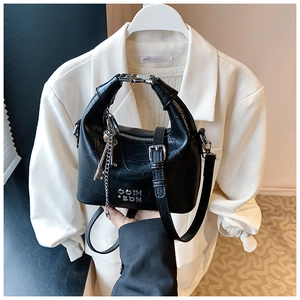 Detail of black crocodile texture bag with metal lock handle and key pendant accessory