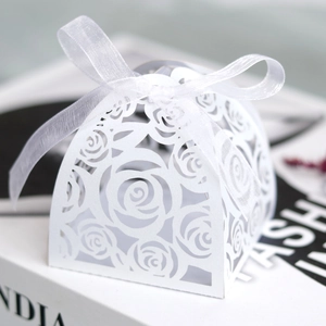 Detail of laser-cut rose patterns on a white wedding favor box with organza ribbon bow