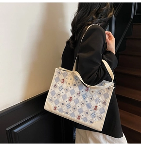 Détail du sac cabas en jacquard à motif d'ours porté par un mannequin dans un escalier
