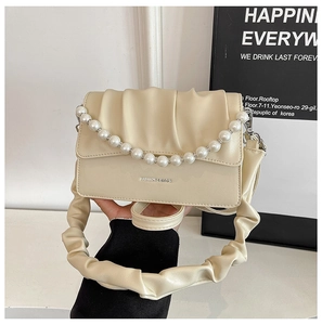 Detail of cream pleated cloud bag featuring large pearl chain and ruched shoulder strap