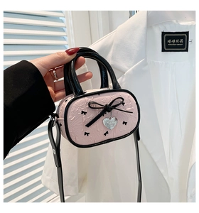 Dettaglio della borsa rosa con texture a rilievo e ciondolo a cuore in argento