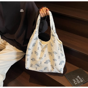 Detailed shot of white canvas tote bag featuring blue koi fish print on a dark wooden background