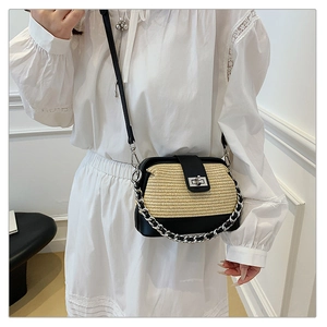 Detail of a chic raffia and black contrast shoulder bag with silver chain and lock