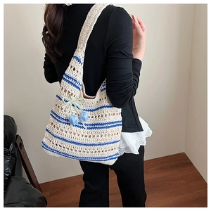 Detailed texture of woven straw bag with blue stripes and decorative tulip pendant