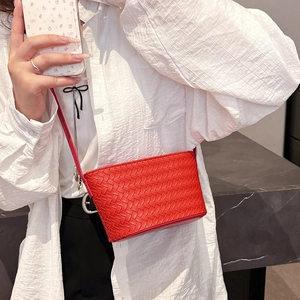 Close-up of a vibrant red woven leather mini crossbody bag styled with a white outfit