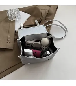 Detail showing high-capacity interior of silver glossy leather bag with daily essentials