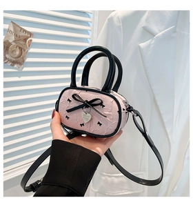 Dettaglio borsa a mano rosa balletcore con fiocco nero e ciondolo a forma di cuore