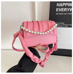 Detail of pink pleated cloud bag with pearl chain decoration and fashion text background