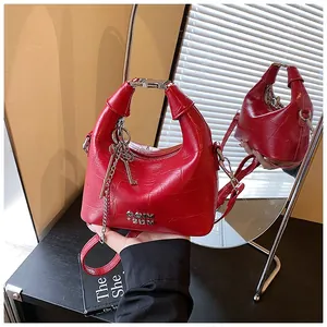 Detailed mirror view of red croc-embossed handbag with silver chain and key charm decoration