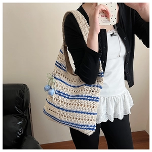 Detail of hand-woven crochet tote bag with blue stripes and floral tulip pendant charm