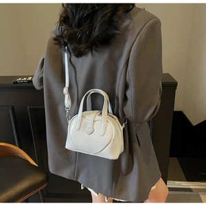 Rear view of a model wearing a white PU crossbody bag with quilted heart-shaped patterns