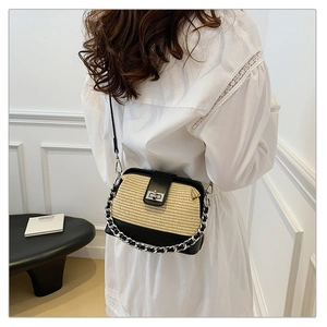 Straw shoulder bag with black leather flap and silver chain shown in a clean studio setting
