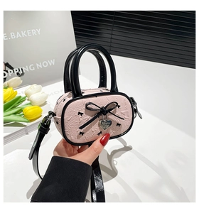 Dettaglio della mini borsa balletcore rosa con fiocco nero e ciondolo a cuore