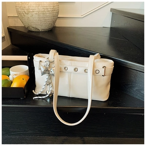 Dettaglio borsa tote in pelle PU crema con occhielli argentati e ciondolo a fiocco