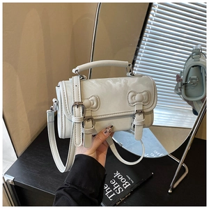 Detail of the light blue handbag showing bow decorations and sleek accordion side panels