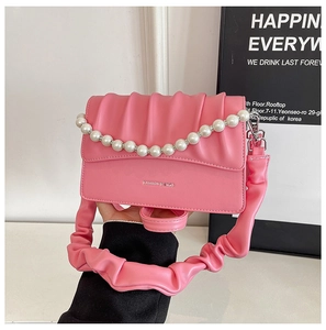 Detail of pink pleated cloud bag featuring pearl handle and textured leather strap