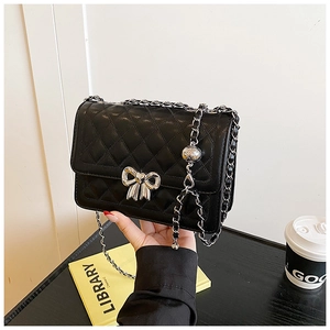 Détail du sac bandoulière matelassé noir avec boucle nœud argent et bandoulière chaîne