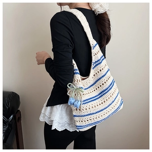 Detail of hand-woven crochet tote bag with blue stripes and decorative blue flower charm