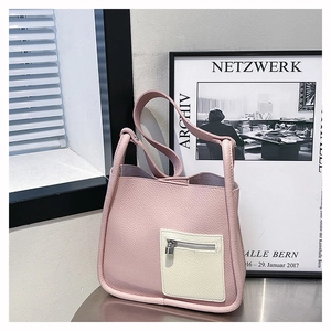 Detail of pink lychee leather bucket bag with white front pocket and silver padlock accent
