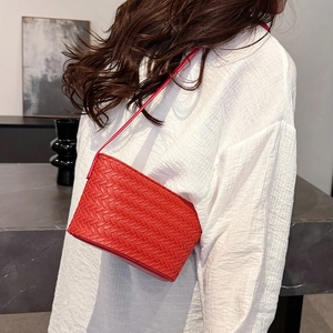 Close-up of bright red woven leather texture on a stylish crossbody bag