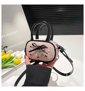 Borsa a tracolla rosa a pieghe con fiocchi in nastro nero e ciondolo a cuore