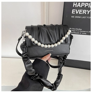Detail of black pleated cloud bag with pearl chain decoration and fashion branding