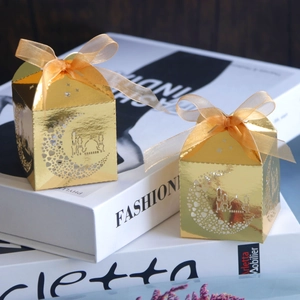 Detailed view of golden镂空 castle gift boxes with orange organza ribbons for wedding candy