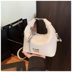 Detail of white crocodile-pattern leather handbag with silver logo and chain accents
