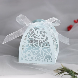 Detail of laser-cut floral pattern on light blue gift box with elegant silk ribbon